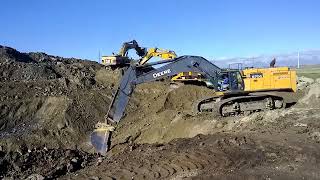 Excavator DEERE 870G and CATERPILAR loading top soil [upl. by Elleirb900]