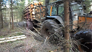 Valtra forestry tractor with big fully loaded trailer logging in wet forest [upl. by Dahsraf]